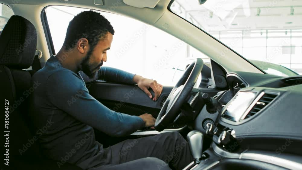 Cheerful young man showing thumbs up while buying a new car Cheerful young man showing thumbs up while buying a new car