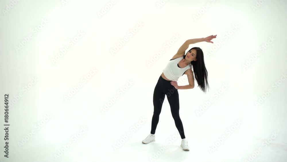 Athletic young beautiful woman brunette with long hair warming exercises in studio on a white background 4K. Athletic young beautiful woman brunette with long hair warming exercises in studio on a white background 4K.