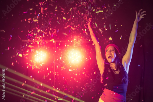 Happy woman dancing under confetti at a party
