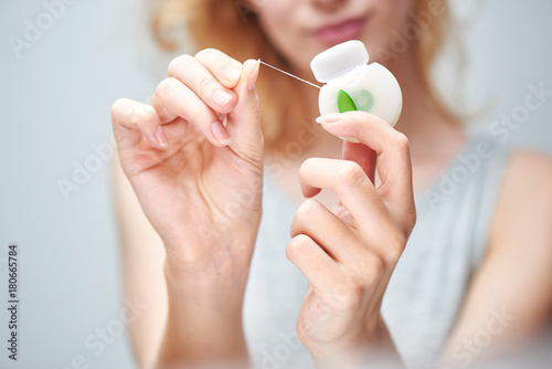 Fotografia A young girl holding a dental floss on white background