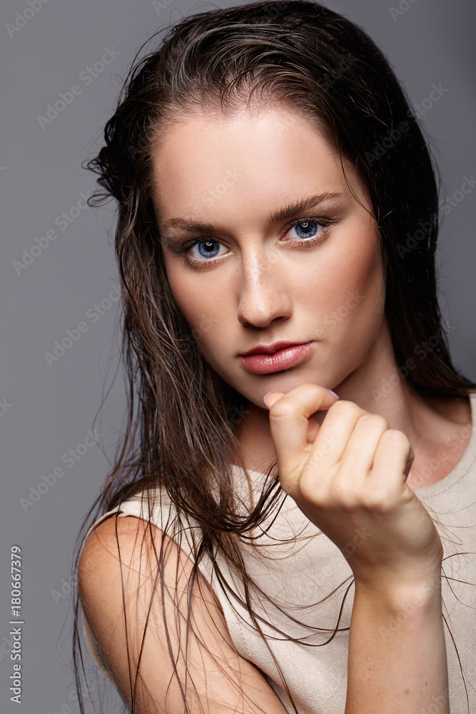 Beauty portrait of young woman. Brunette girl with bright blue eyes and day female makeup on gray background Beauty portrait of young woman. Brunette girl with bright blue eyes and day female makeup on gray background