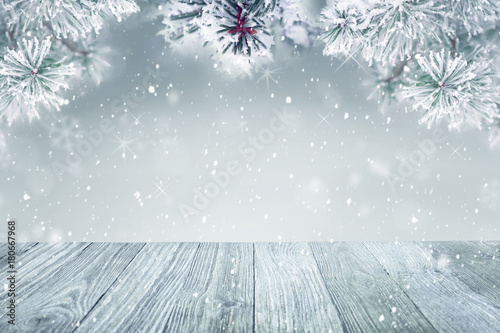 Winter background, falling snow on pine tree and wooden deck