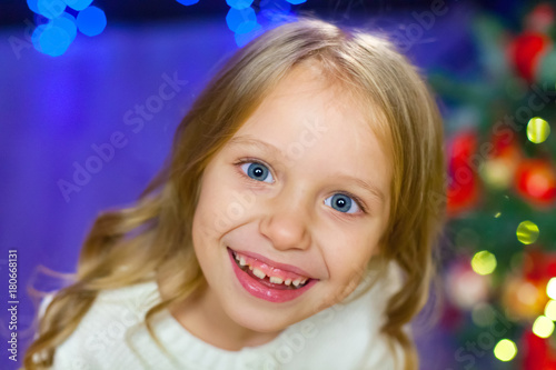 A large portrait of a child on a background of Christmas lights