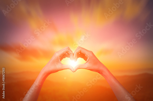 conceptual heart shape or symbol made of woman and silhouette over a sky at sunset background. love, valentine, romantic, couple, wedding, romance