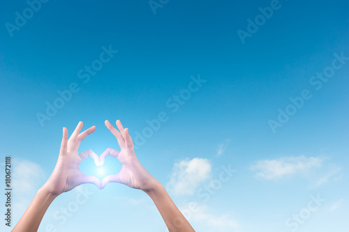 two hands making a heart shape in the blue sky