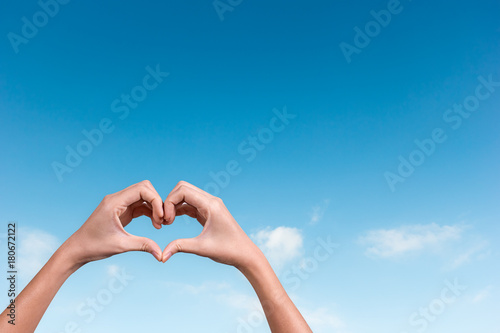 hands making a heart shape in the blue sky