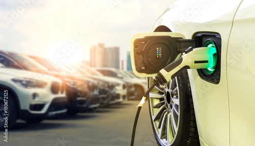 Power supply connect to electric car for add charge to the battery. Charging re technology industry transport which are the future of the Automobile with city background.