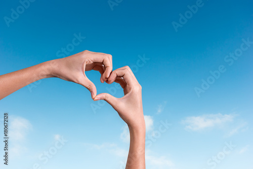 hands making a heart shape in the blue sky