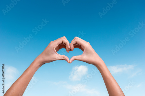 hands making a heart shape in the blue sky