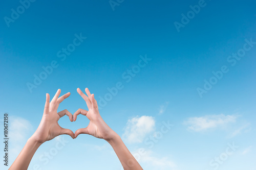 two hands making a heart shape in the blue sky