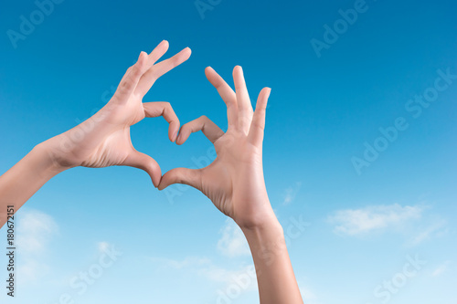 two hands making a heart shape in the blue sky