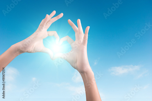 two hands making a heart shape in the blue sky