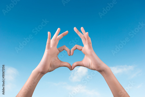 two hands making a heart shape in the blue sky