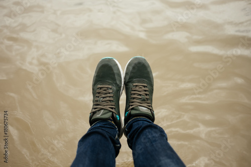 top view. foot of women wearing shoe, jeans stand on water surface are background. image for body, abstract, nature, travel, equipment, fashion, lifestyle concept