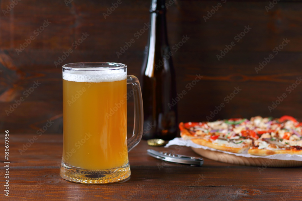 Mug of light beer and pizza with smoked meat and vegetables on dark wooden background.
Mug of light beer and pizza with smoked meat and vegetables on dark wooden background.