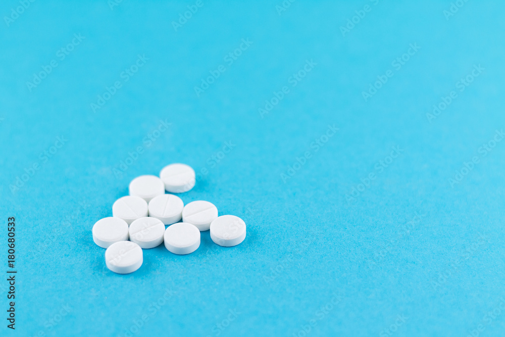 White pills with copy space on blue background. Focus on foreground, soft bokeh White pills with copy space on blue background. Focus on foreground, soft bokeh