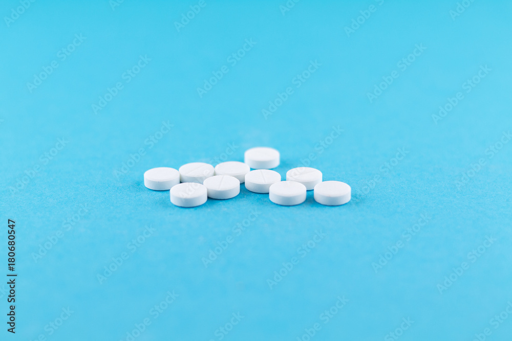 White pills with copy space on blue background. Focus on foreground, soft bokeh White pills with copy space on blue background. Focus on foreground, soft bokeh