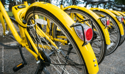 Close up Bicycle tail light on group of yellow vintage bike parking in the Park to service the touristi n bike sharing concept. photo