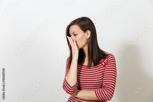 Pretty European worried and pensive brown-haired woman with healthy clean skin and headache, dressed in red and grey clothes lost in thought and conjectures, on a white background. Emotions concept. © ViDi Studio