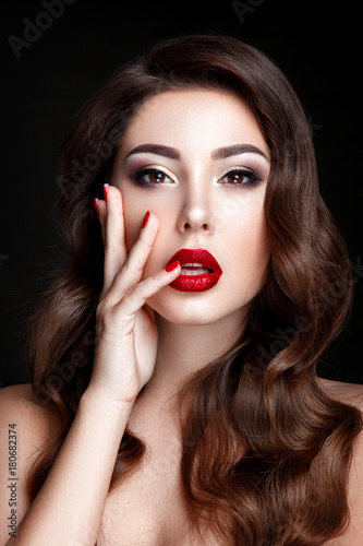 Fashion woman portrait on black background with red shiny lips and red nails.