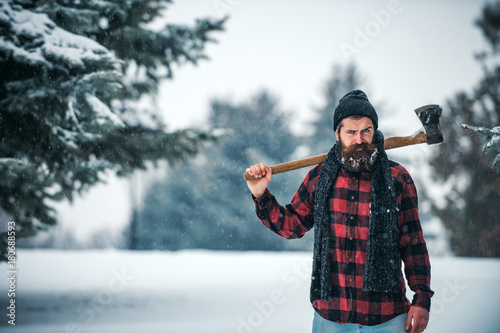 Christmas hipster lumberjack with ax in wood photo