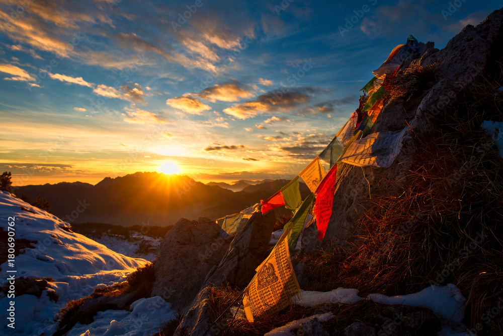 Flags of Tibetan prayers in the mountains with the colors of a warm sunset