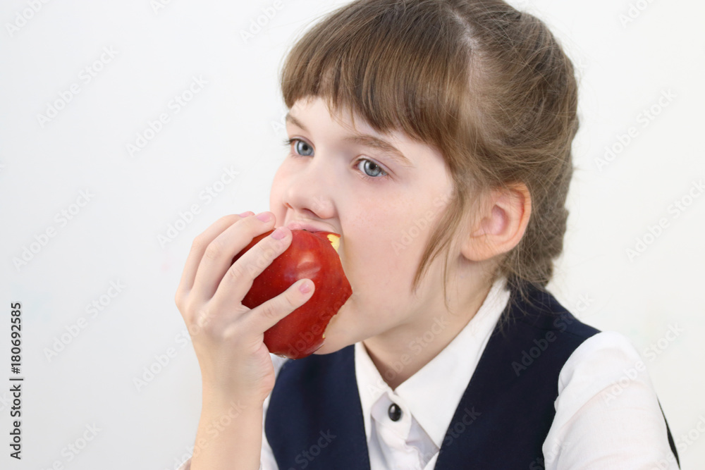 Portrait of pretty schoolgirl in uniform eating red apple in white studio Portrait of pretty schoolgirl in uniform eating red apple in white studio