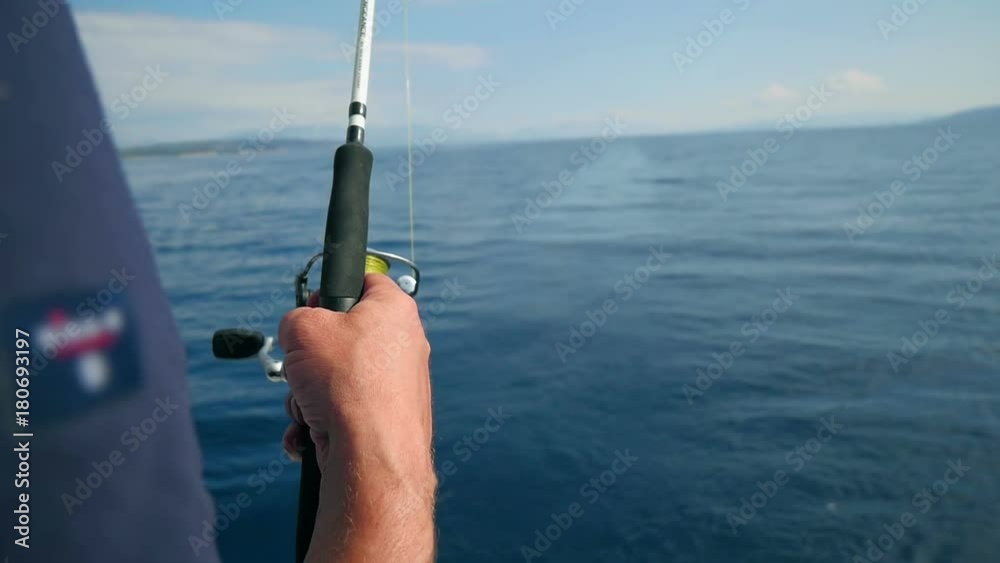 Man holding a fishing rod fishing in sea at back side of sailing boat. Sailing boat slowly moving. Shot in slow motion hd. Man holding a fishing rod fishing in sea at back side of sailing boat. Sailing boat slowly moving. Shot in slow motion hd.