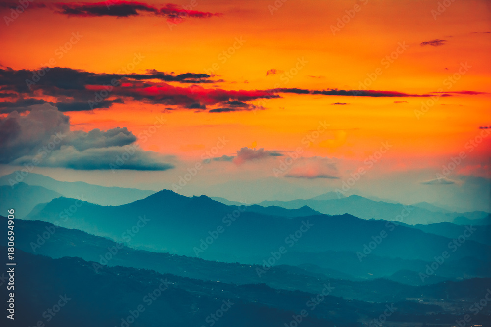 Magnificent sunset views of the mountain range with the altitude of the aircraft. Picturesque and gorgeous evening scene with bright orange sky. Color toning effect. Beauty world.