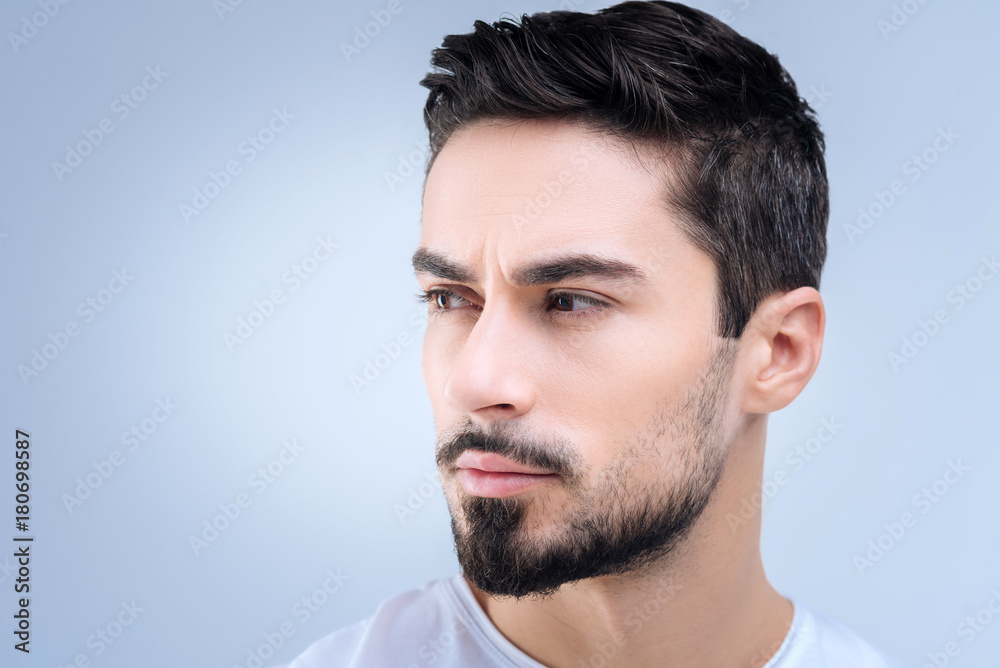 Suspicious. Concentrated serious young man feeling uncomfortable while thinking about a strange situation at work and having a suspicion about it