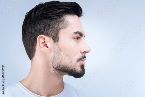 Nice haircut. Calm unemotional young man standing quietly and showing his new haircut after visiting a qualified barber