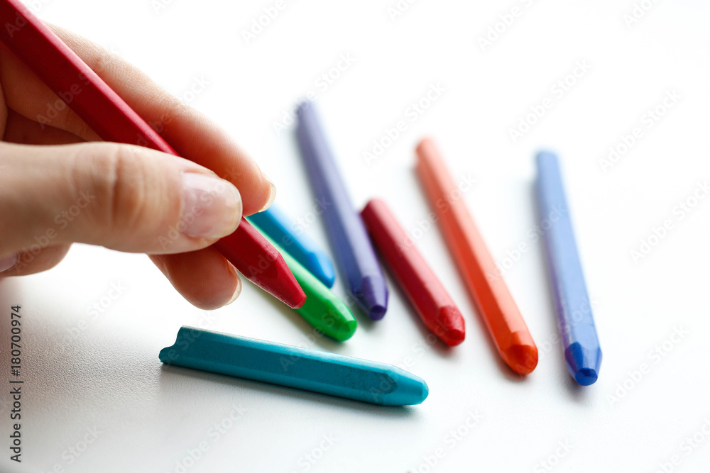 Hand holding colored crayons. Isolated on a white background. Closeup Hand holding colored crayons. Isolated on a white background. Closeup