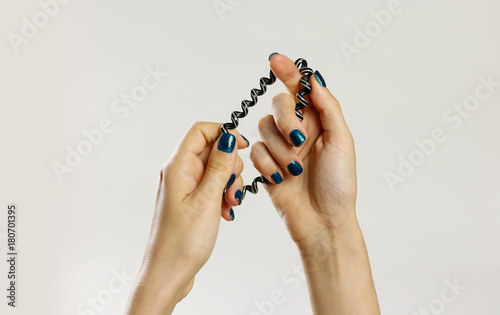 Female hand holding plastic spirally scrunchie. Isolated on gray background. Closeup