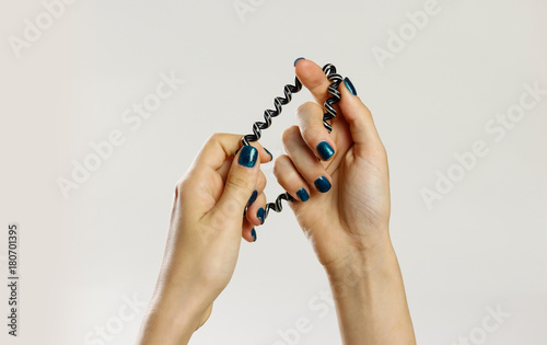 Female hand holding plastic spirally scrunchie. Isolated on gray background. Closeup photo