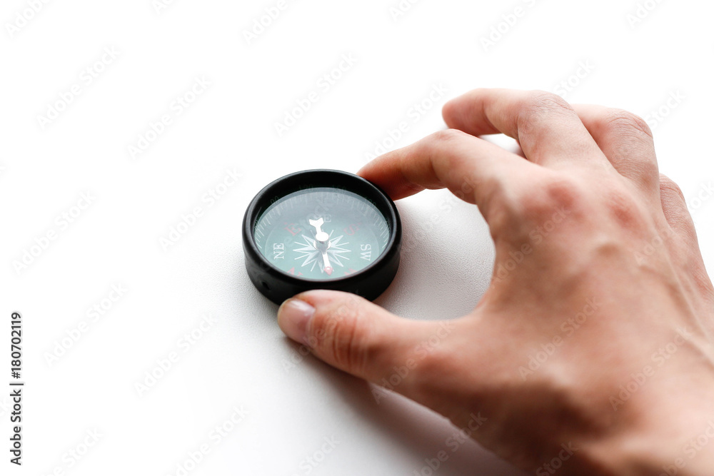 The hand holds a compass. Closeup. Isolated on a white background The hand holds a compass. Closeup. Isolated on a white background