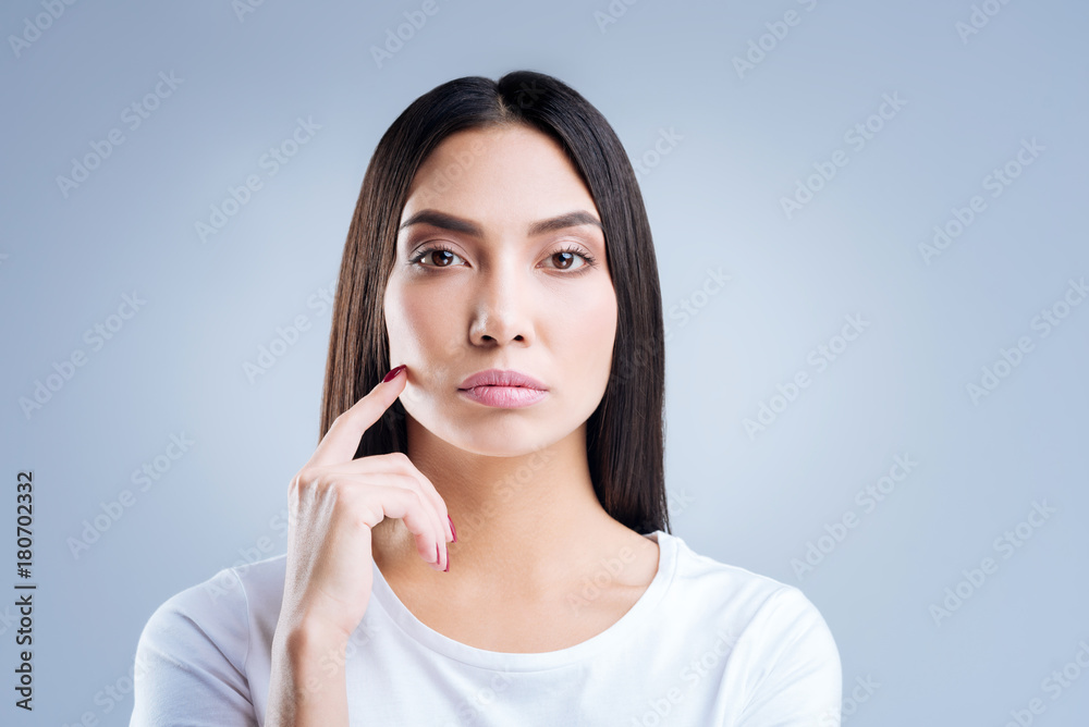 Strict employer. Young professional smart businesswoman looking strict and serious while standing against the blue background and listening to the workers of her company Strict employer. Young professional smart businesswoman looking strict and serious while standing against the blue background and listening to the workers of her company