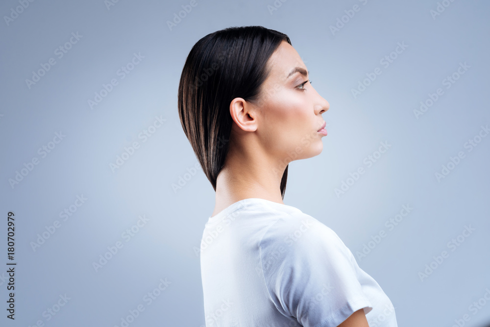 Strict doctor. Calm responsible professional doctor looking strict and serious while standing in her consulting room and waiting for the patients Strict doctor. Calm responsible professional doctor looking strict and serious while standing in her consulting room and waiting for the patients