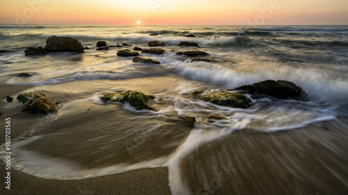 Sunrise over the black sea , big waves and rocks.