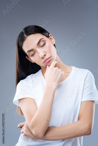 Falling asleep. Young exhausted beautiful woman standing with her eyes closed against the blue background and falling asleep while being at work