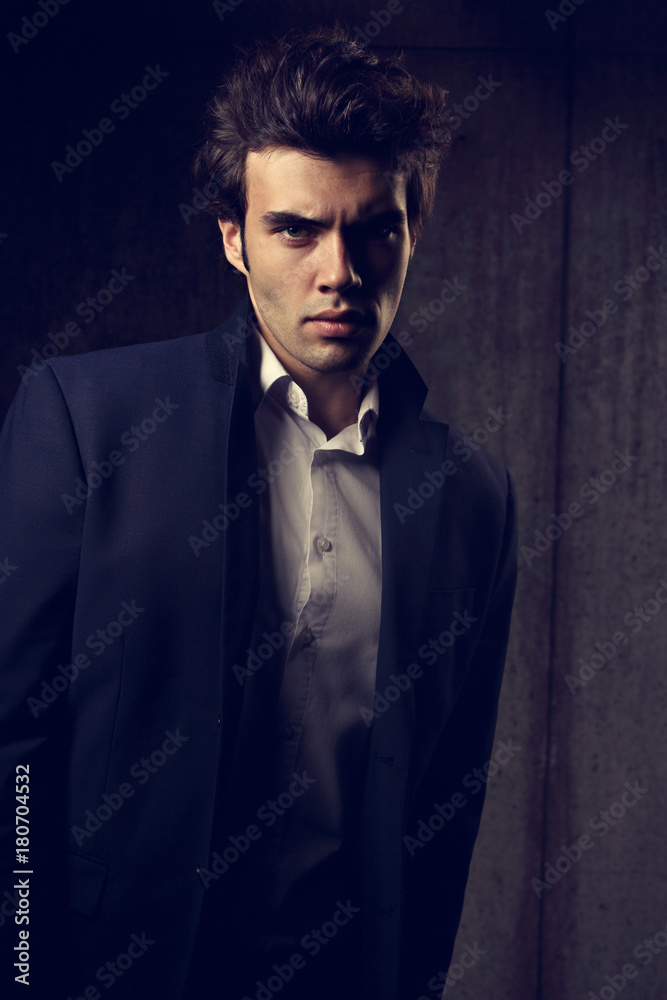 Handsome male model posing in fashion suit and white style shirt looking on dark shadow background. Closeup portrait Handsome male model posing in fashion suit and white style shirt looking on dark shadow background. Closeup portrait