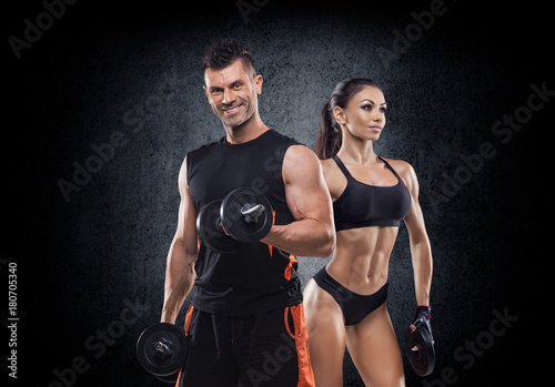 beautiful young sporty sexy couple showing muscle and workout in gym during photoshooting