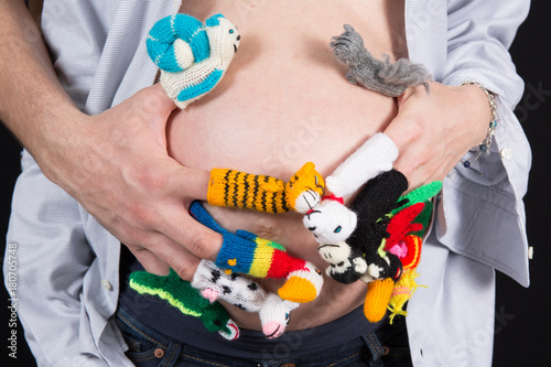 Wool figurines on a woman fingers with her hands on her pregnant belly