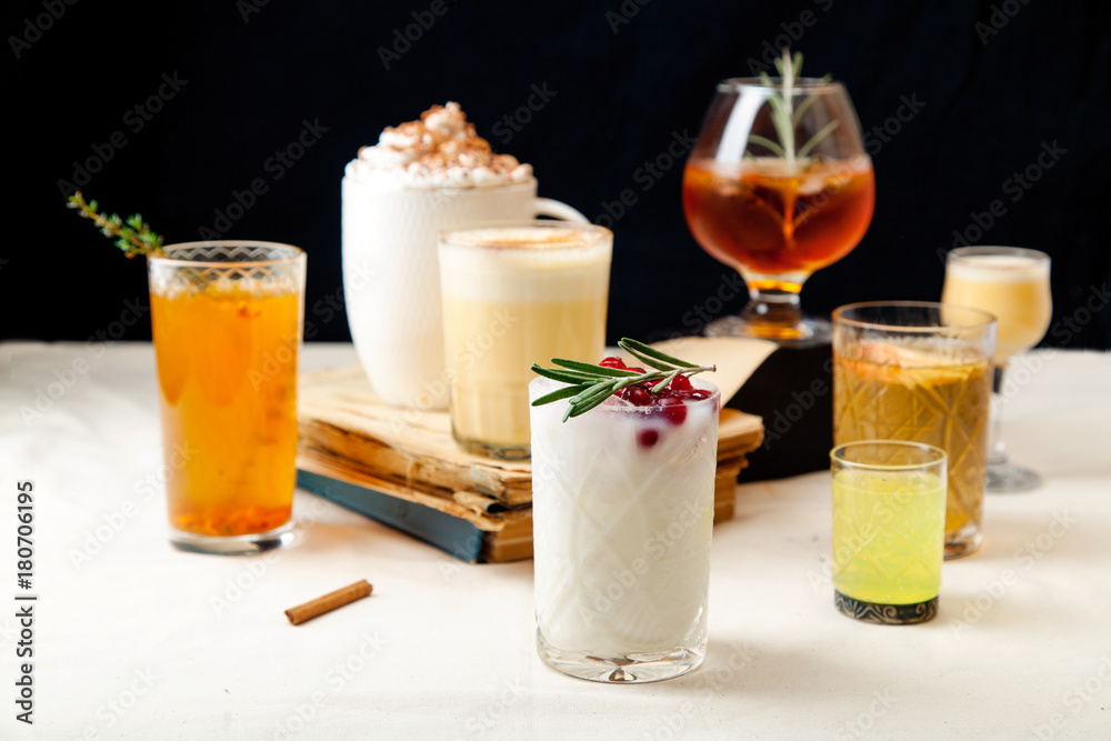 Set of various winter cocktails: mulled wine, eggnog, limoncello, old-fashioned, coconut margarita. Black background, white linen tablecloth.