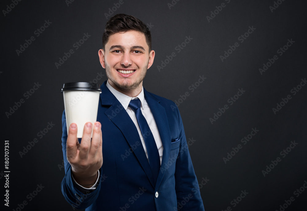 Smiling businessman holding out a disposable coffee cup.