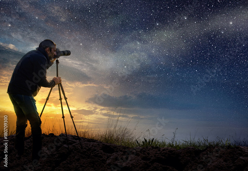 man taking a photo at dawn with starry sky