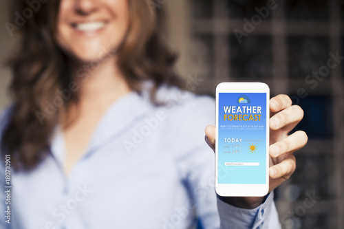 Happy woman showing a mobile phone with weather forecast in the screen. photo