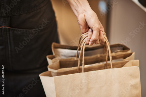 Professional waiter holding packages with coffee beans photo
