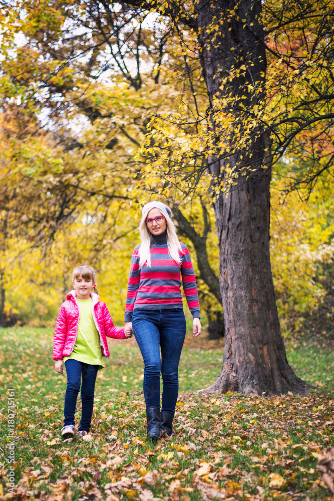 Mother and daughter walking trough forest in fall Mother and daughter walking trough forest in fall