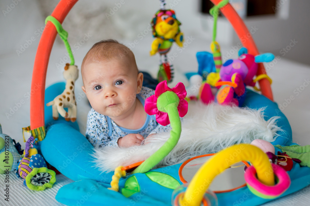 Cute baby boy on colorful gym, playing with hanging toys at home - obrazy, fototapety, plakaty 