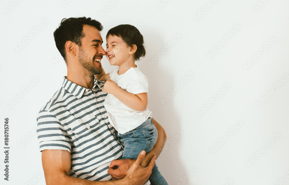 Naklejka premium Funny happy dad and daughter play and cuddle together against white background. Good relationship of parent and child. Happy family moments of father and toddler girl. Childhood and parenthood care.